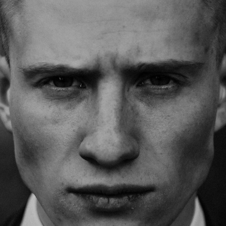 Portrait en noir et blanc d'un homme au regard intense et expression sérieuse.