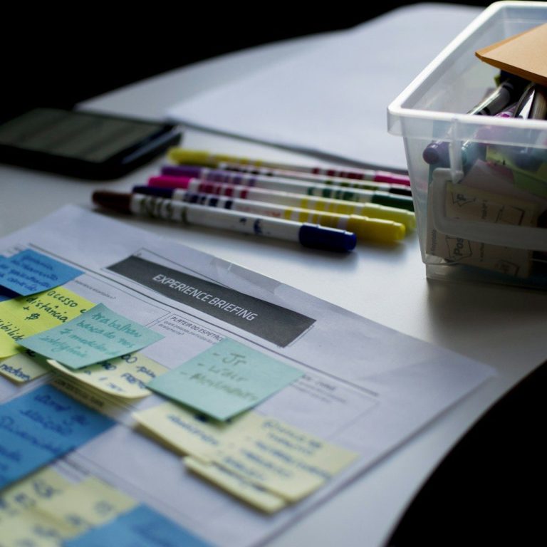 Bureau avec des notes autocollantes, des stylos et un téléphone portable.