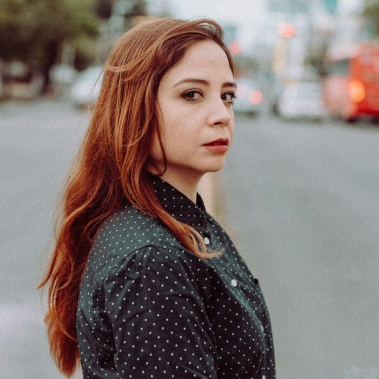 Femme brune avec des cheveux longs et lisses, regard sérieux, tenue à pois.