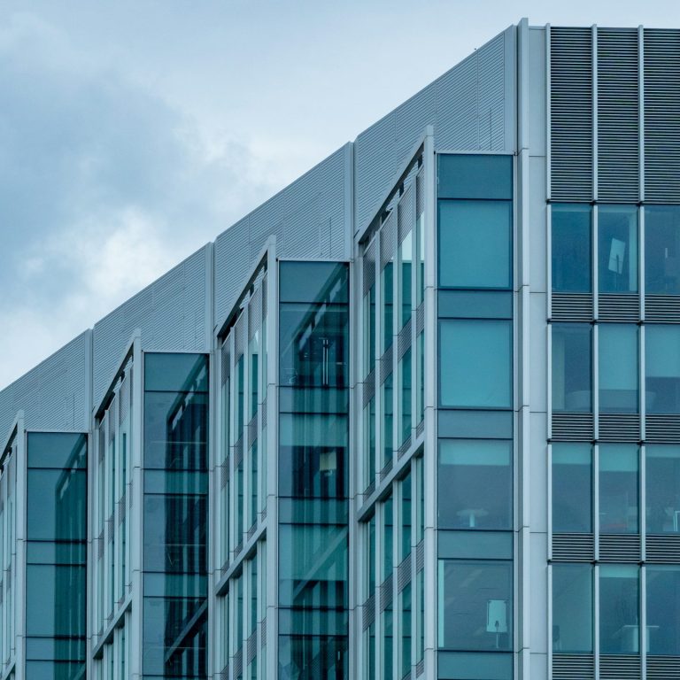 Façade moderne d'un bâtiment avec des fenêtres en verre et un toit pointu.